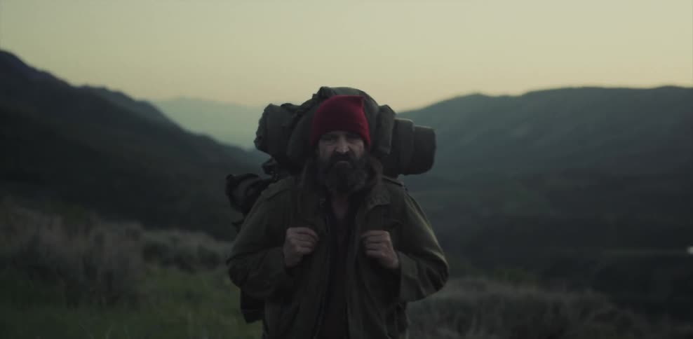 Man wearing a backpack stands in a field