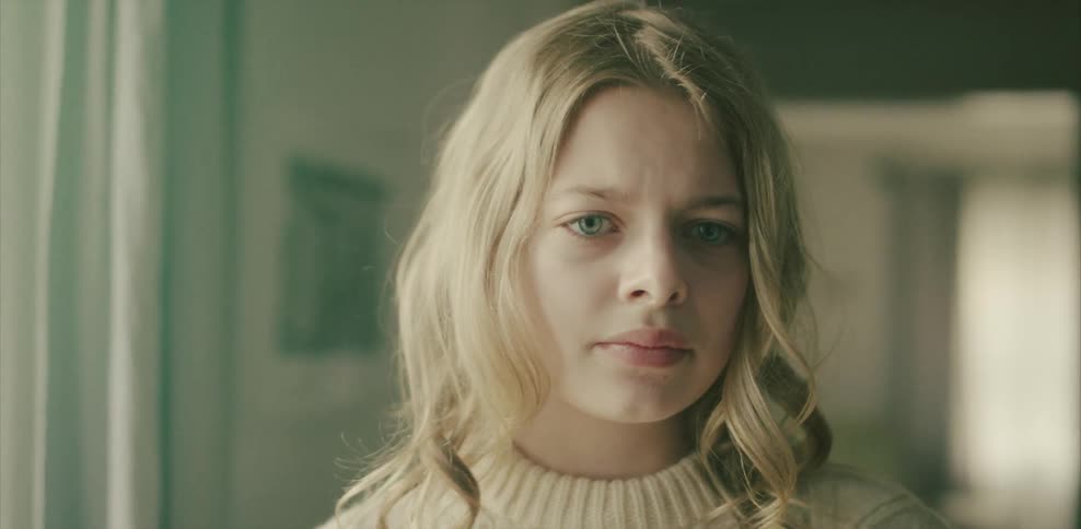 A blonde haired woman stares out looking sad