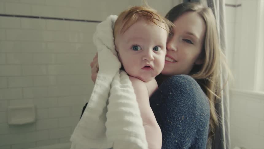 Woman drying a baby off after taking it out of the bathtub