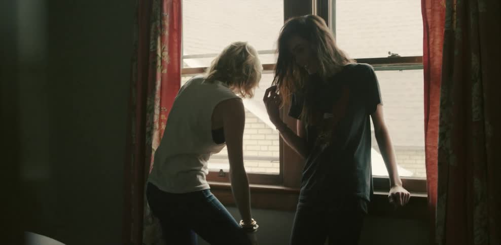 Two women lean against a window