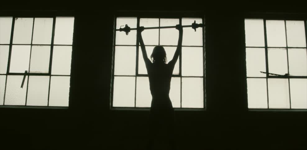 Skinny man raises small barbell above his head