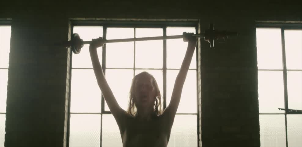 A thin blonde man lifts weights