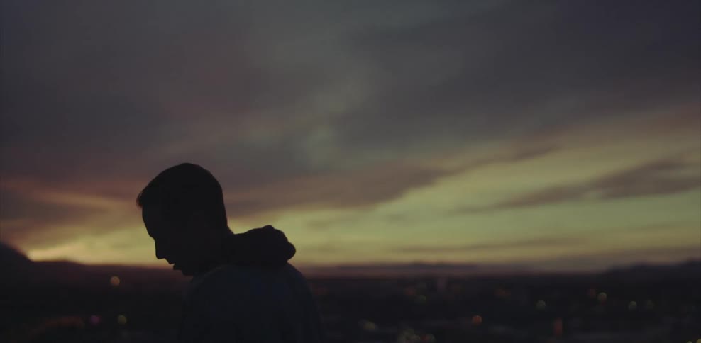 A man stands outside at sunset