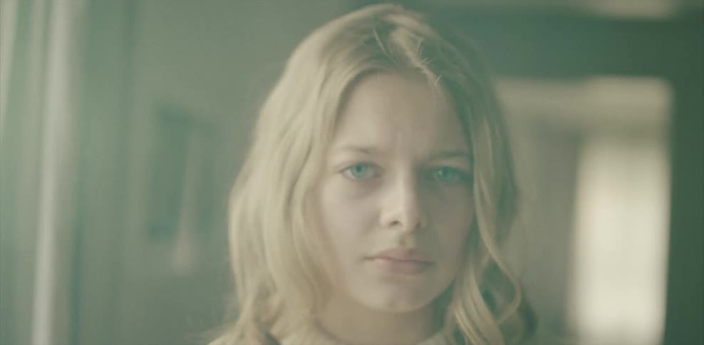 A blonde haired woman stares out looking sad