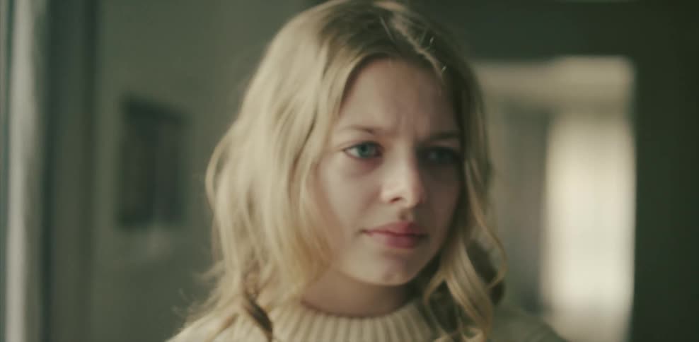 A blonde woman in a room looks at something