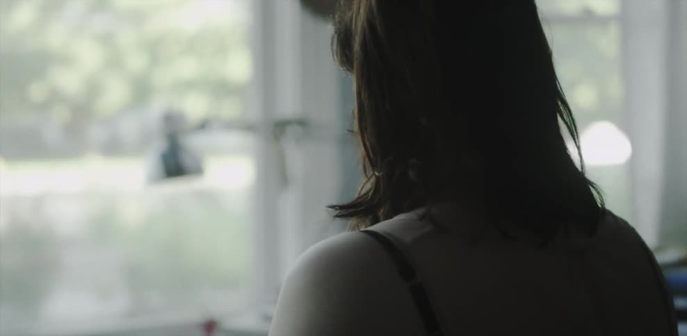 A woman is standing by her window looking outside