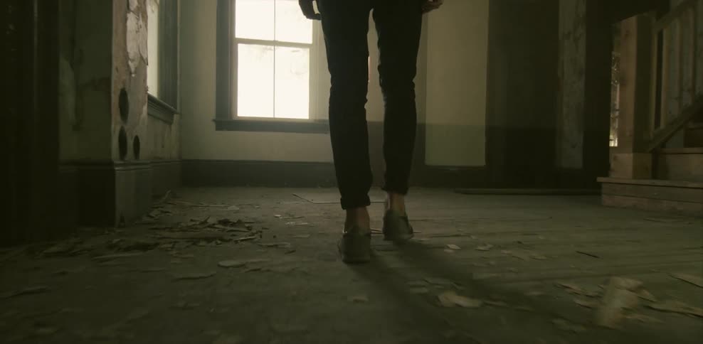 Person walking through an empty room to look out a window