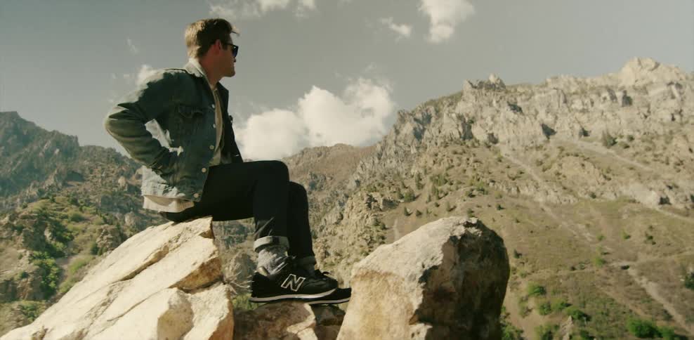 Man wearing denim jacket and sitting on a rock