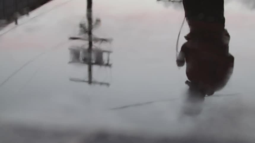 A man's reflection in the puddle is of him walking back and forth