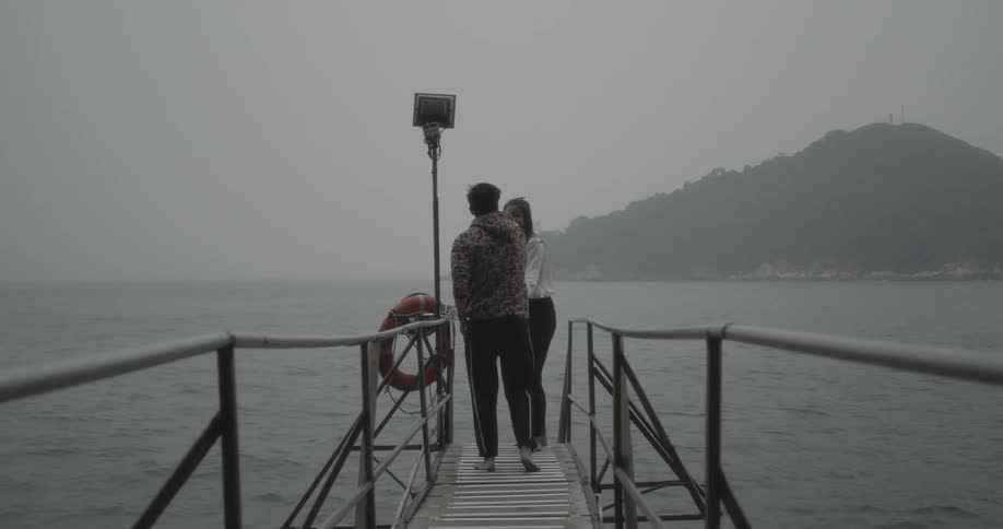 A man and woman run to the end of a dock and take a selfie