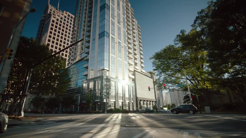 Man walks across a downtown street in front of a sunlit skyscraper