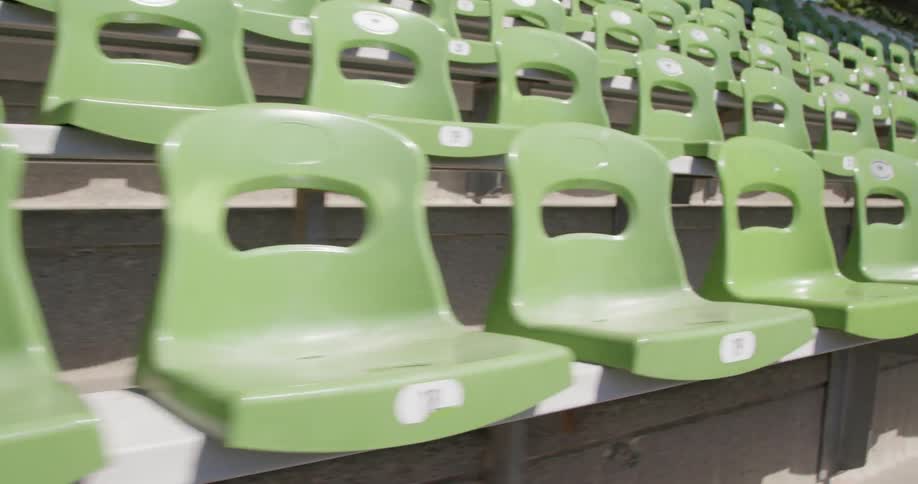 Green and white bleacher seats line a stadium