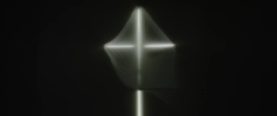 Black fabric blows around a white cross