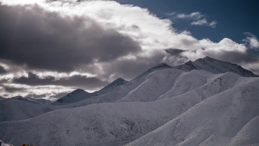 Clouds blowing over snow-capped mountains