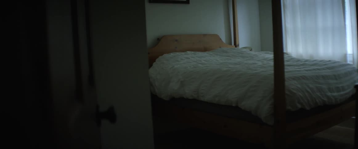 A four-poster bed is seen through a doorway