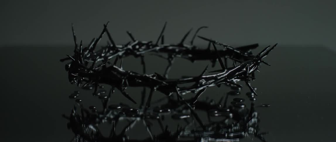 A thorny headpiece sits beside drops of liquid