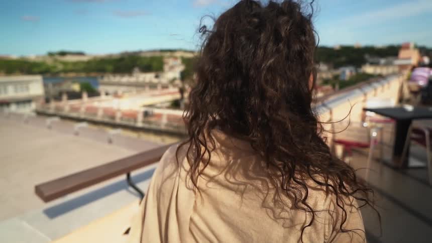 Woman standing on a rooftop walks towards the edge