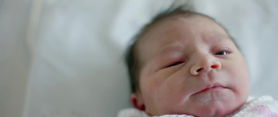 A baby with brown hair is in the crib