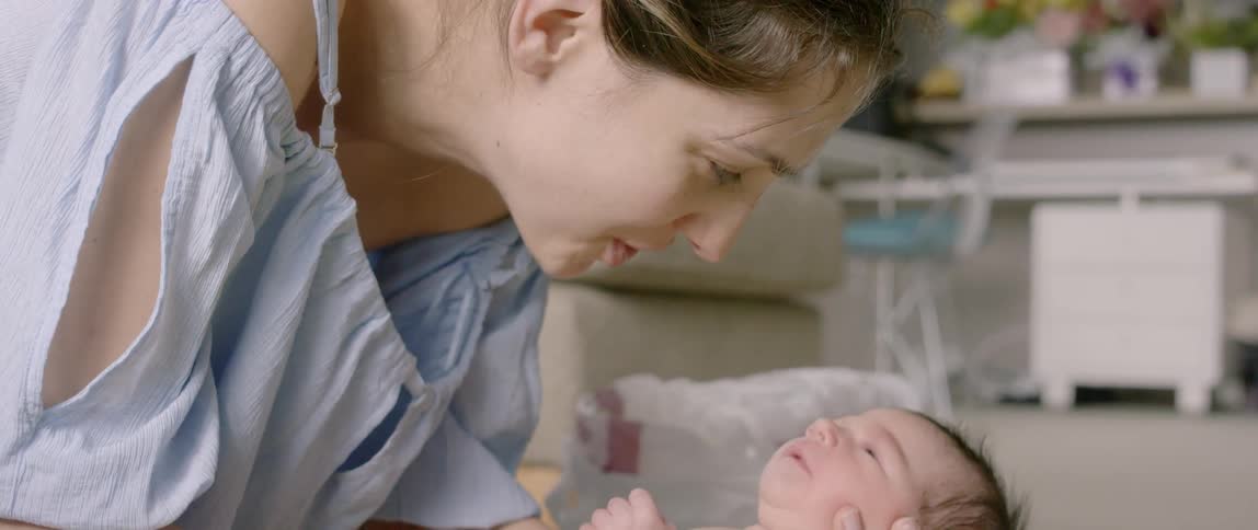A woman smiles down at the baby she's holding