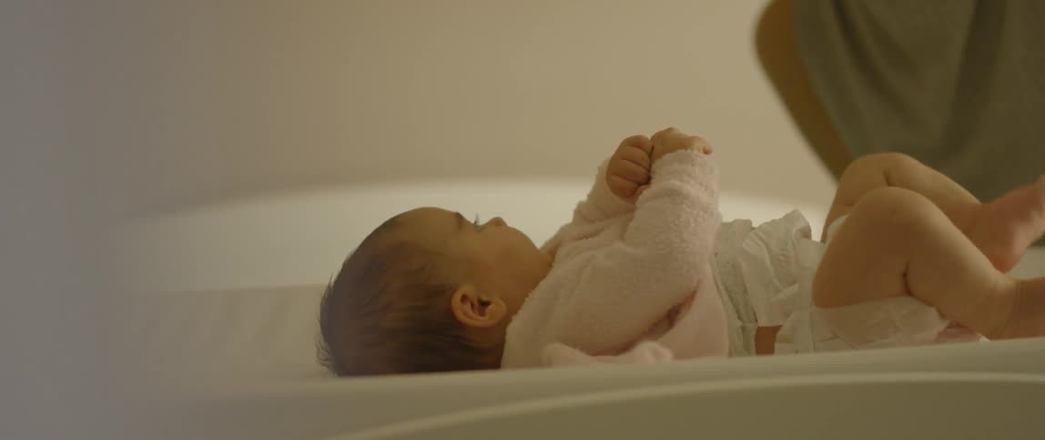 A baby on a changing table kicks her legs