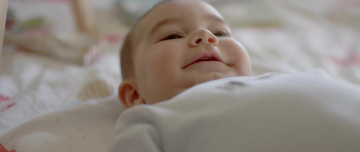An infant laughs while laying down
