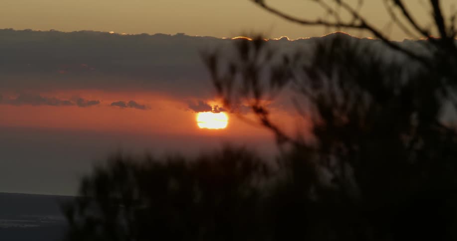 The sun is setting behind the clouds