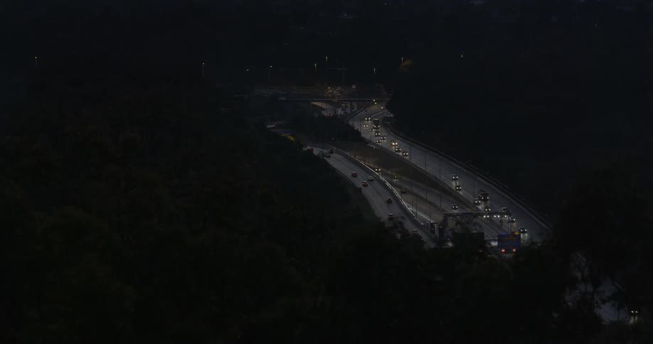 Vehicles travel down a busy highway at night
