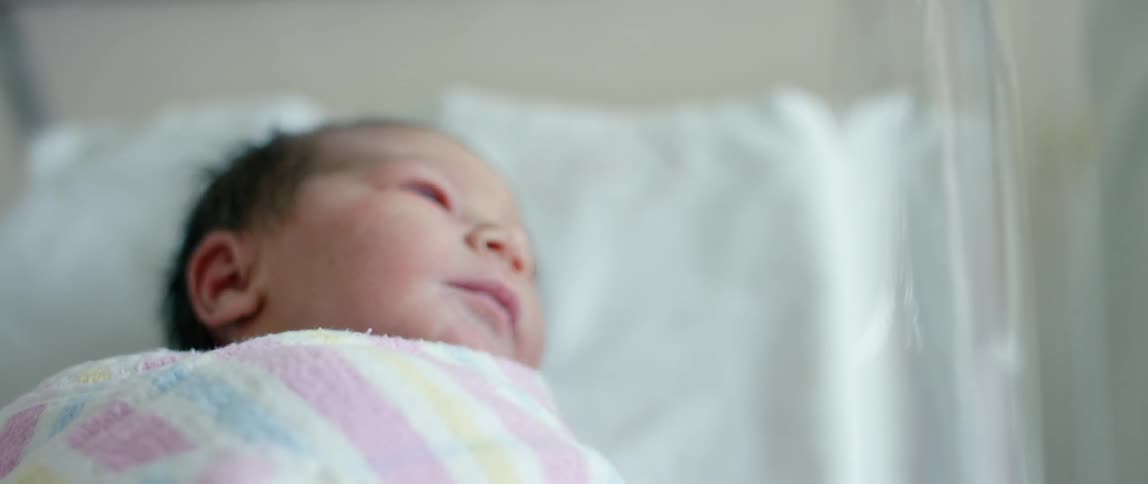A newborn baby in a hospital crib