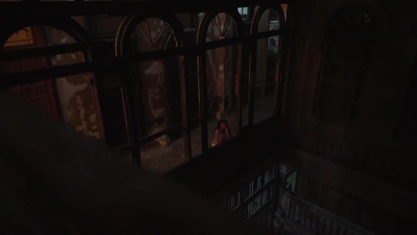 A woman is looking into a darkened library in an old building