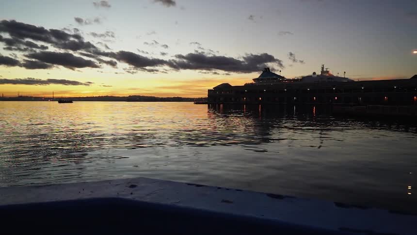 Cars driving down a road next to a body of water at sunset