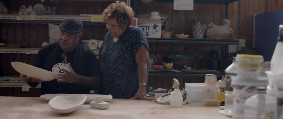 A man and woman talk in a ceramic workshop
