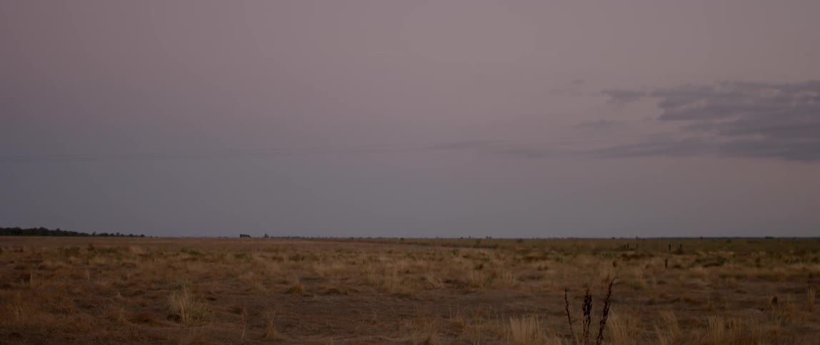 View of a barren field at sunset