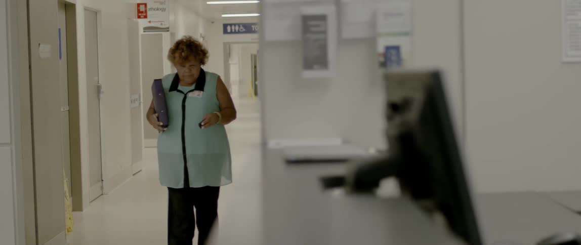 A female doctor walks down a hospital corridor checking her pager