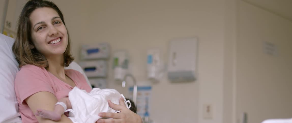 A woman smiles while holding a new born
