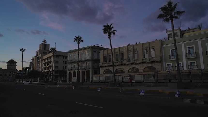 The buildings are lined with palm trees at dawn