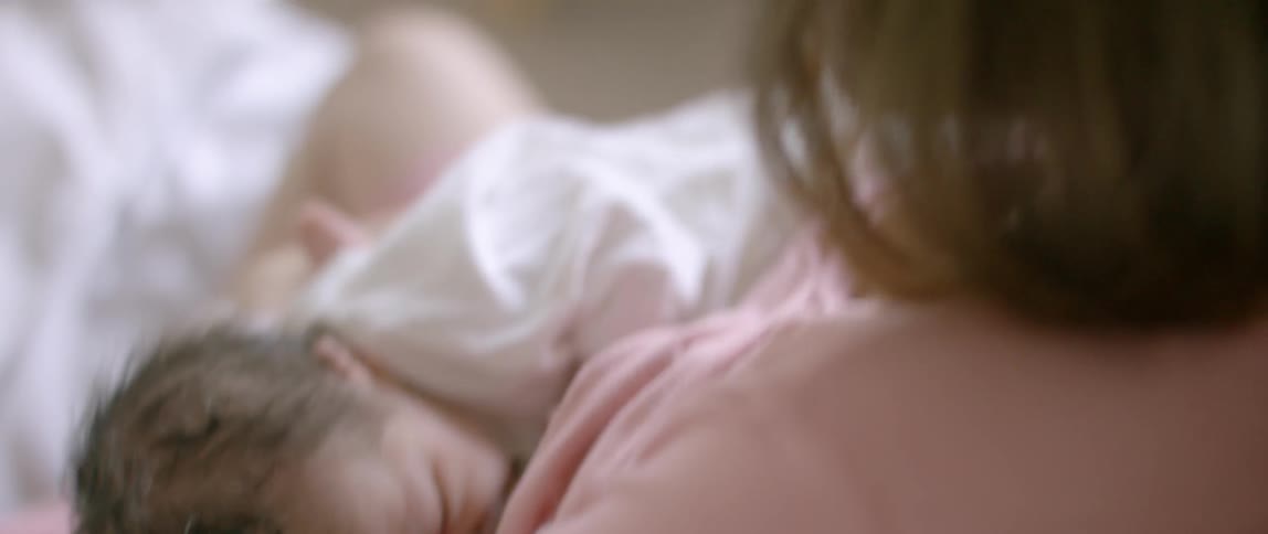 A woman breastfeeds a newborn