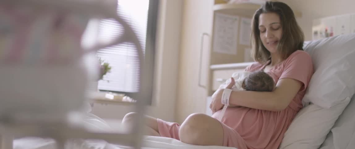 Woman sits in a hospital bed holding an infant
