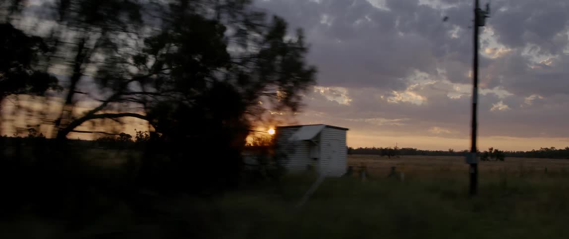 The sun sets over a rural landscape