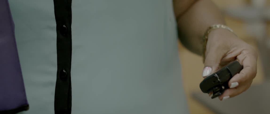 A woman picks up a beeper and presses buttons