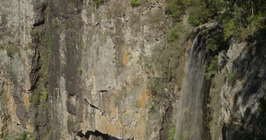 Water falls off the side of a stone mountain