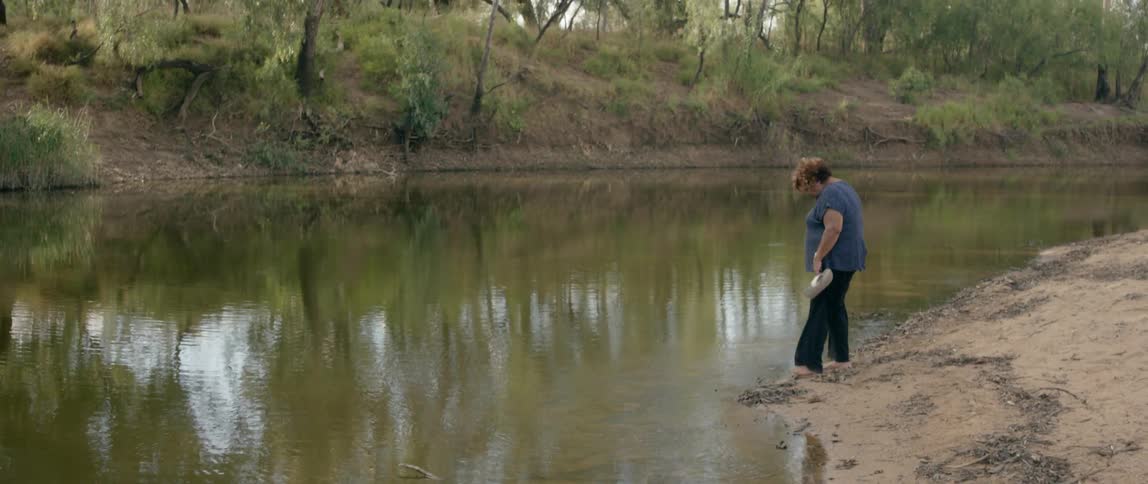 A woman is walking along the pond edge