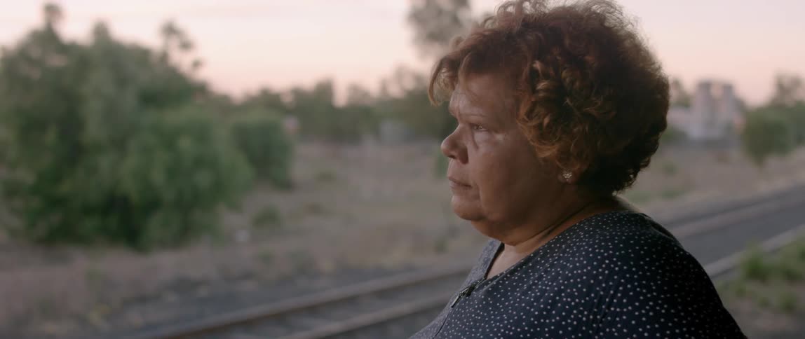 A woman stands outside near train tracks