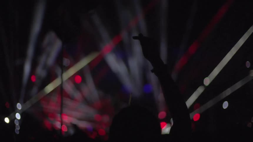 Hands outstretched at a light show