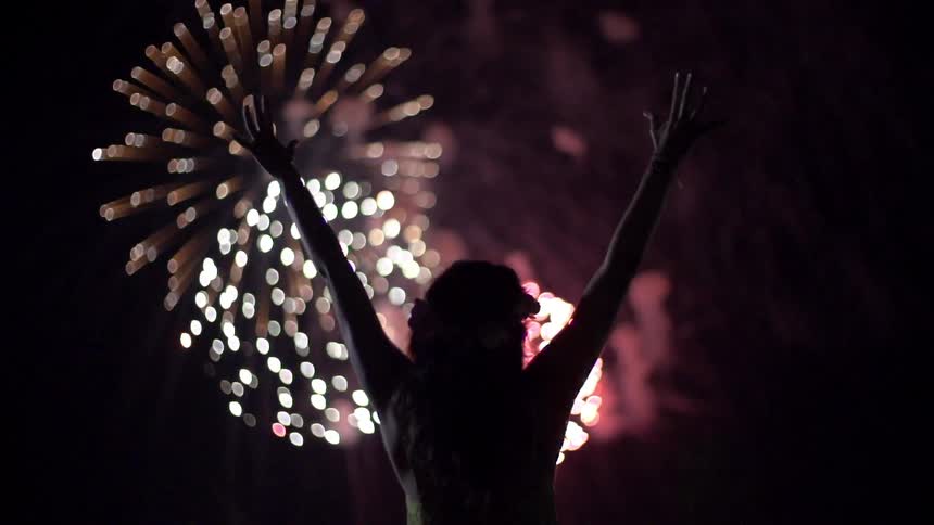Woman watching fireworks exploding in the night sky