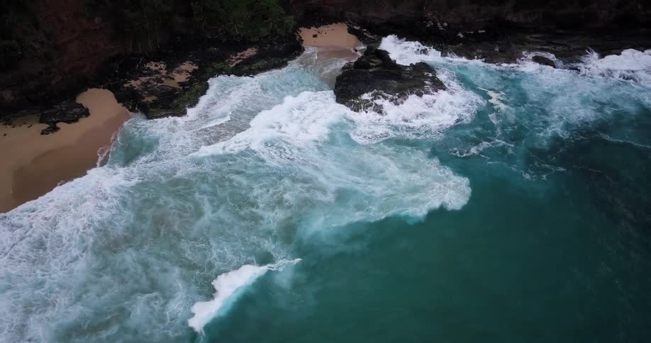 Waves break against rocks and come to shore