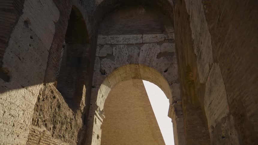 The sun shines through a stone arch