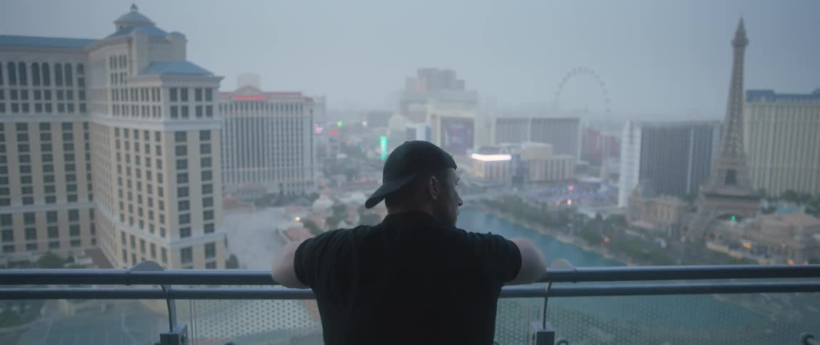 A man stands on a balcony overlooking las vegas on a cloudy day
