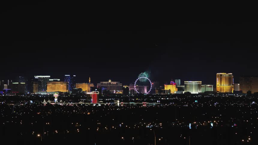Fireworks explode over a cityscape at night