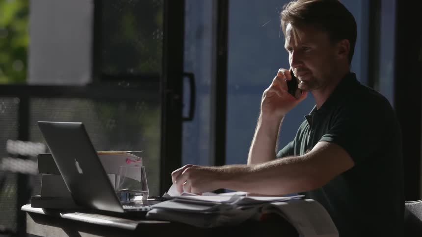 A man is working talking on the phone and taking notes