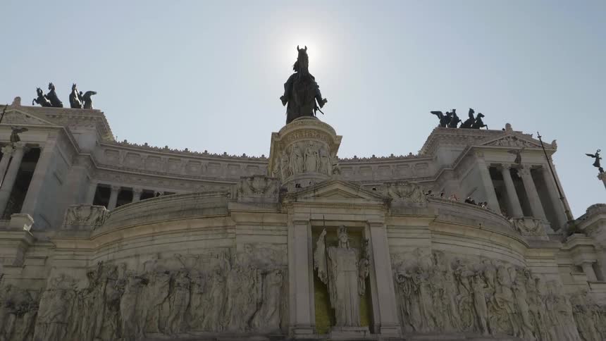 The large building has many statues on the roof